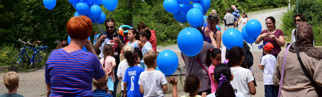 Eine Gruppe von Menschen lässt blaue Luftballone steigen.